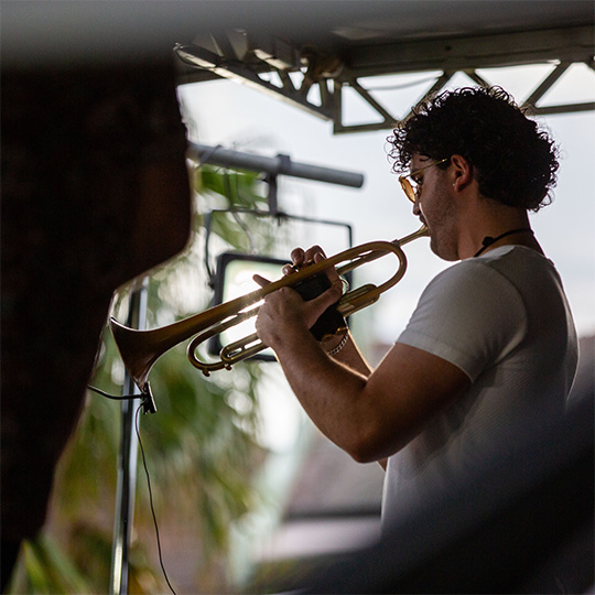A trumpeter performing on an outdoor festival stage.